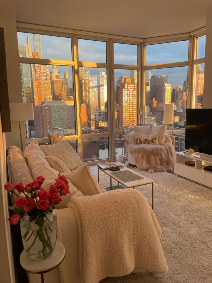 a living room filled with furniture and large windows overlooking the cityscape at sunset