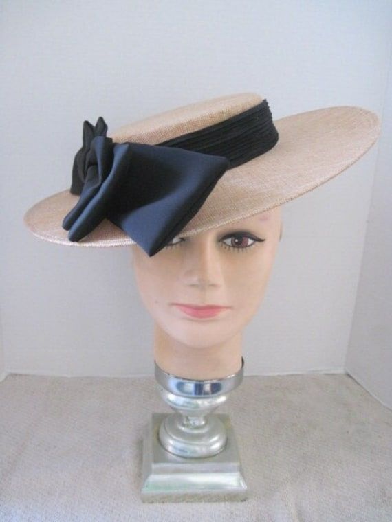 *  This classic design features a tan Sinamay hat form with a jumbo black satin bow.  It is slightly oval and the bow can be worn on either the right side or left side of the head. *  The black elastic band secures the design and it is light weight and comfortable to wear. *  Designed for any Easter Event, Mother's Day Celebration, Derby occasion, Wedding Event, Fashion Show, Birthday Celebration, Garden or Tea Party, Baby or Wedding Shower, Ladies Gathering or just for fun. Classic Black Boater Hat For Party, Adjustable Ribbon Hat For Kentucky Derby, Adjustable Hat With Ribbon For Kentucky Derby, Adjustable Brimmed Boater Hat For Formal Occasions, Formal Adjustable Wide Brim Boater Hat, Adjustable Wide Brim Boater Hat For Formal Occasions, Formal Wide Brim Boater Hat, Formal Flat Brim Fascinator With Adjustable Fit, Adjustable Flat Brim Formal Fascinator