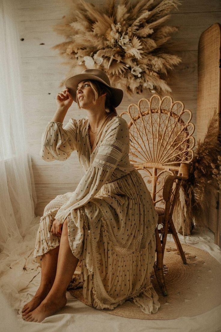 a woman in a dress and hat sitting on a chair next to a large fan