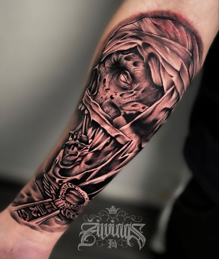 a man's arm with a black and grey tattoo on it, depicting a skeleton holding a cross