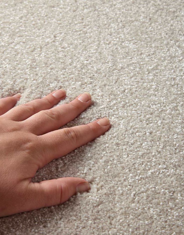 a person's hand on top of a gray carpet