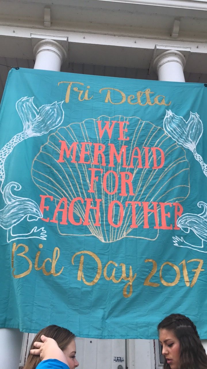 two women standing in front of a sign that says we mermaid for eachother