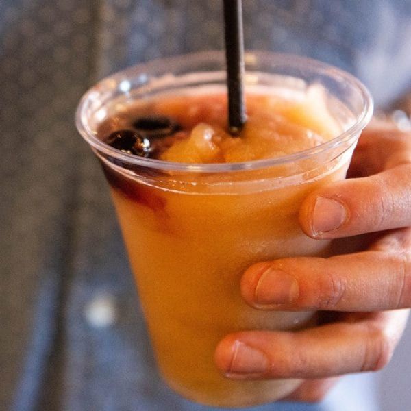 a person holding a drink in their hand with a black straw sticking out of it