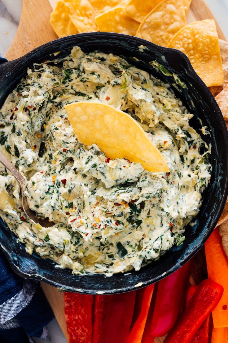 a skillet filled with spinach dip surrounded by tortilla chips