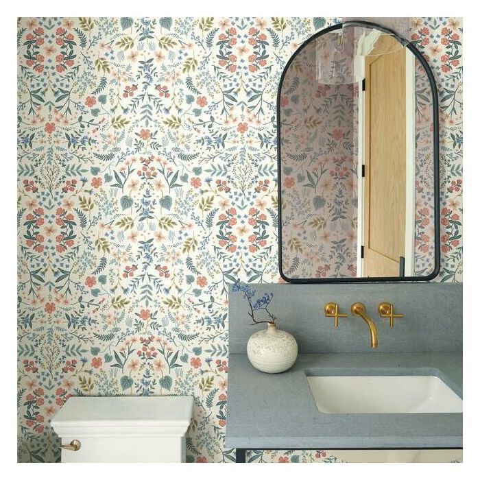 a bathroom with floral wallpaper and a mirror above the sink, along with a white toilet