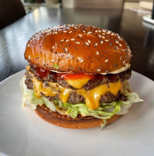 a cheeseburger with lettuce and tomato on a white plate