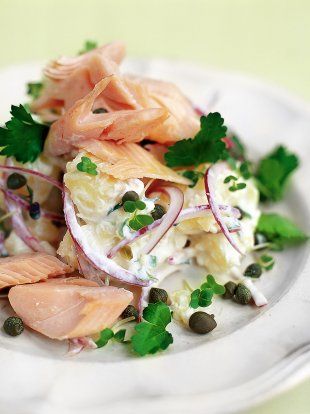 a white plate topped with lots of food and garnished in green onions, capers