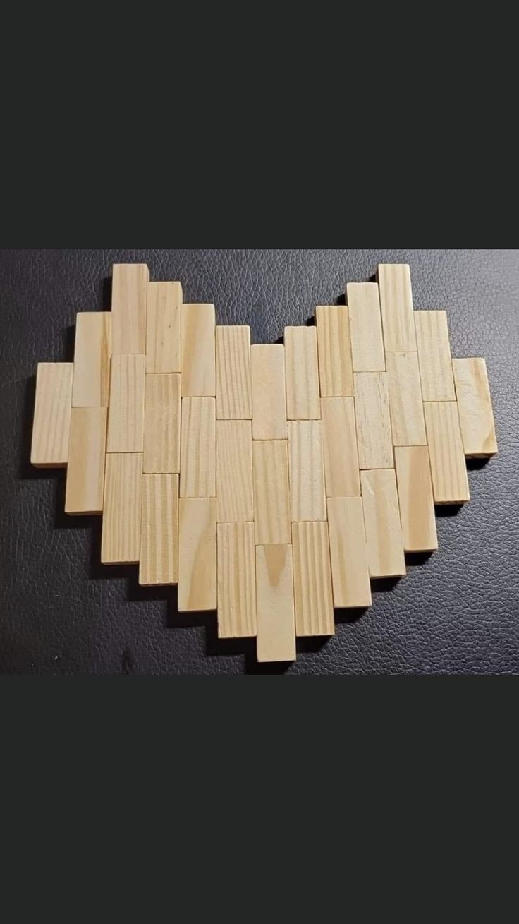 a heart made out of wooden planks on a black surface with one piece missing