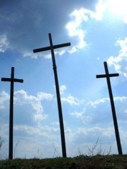 three crosses are standing in the grass under a blue sky