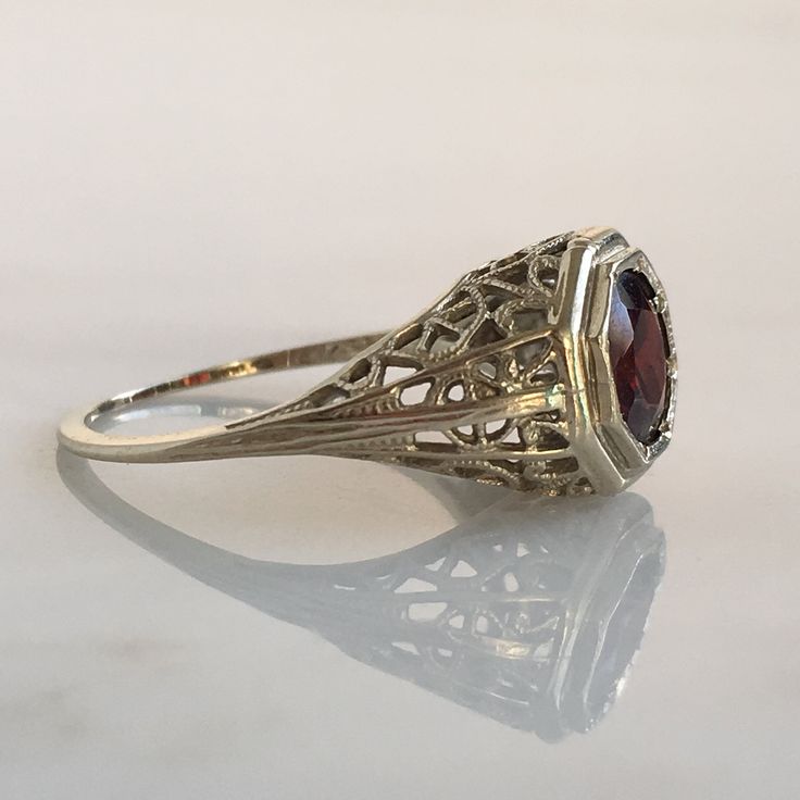 Details: Stunning Art Deco Period garnet and 14K white gold filigree ring! The stone measures 6mm, and the is 5.6mm above the finger at the highest point on the ring. The filigree is beautiful on this ring, and is in lovely shape. This is a stunning ring--you will not be disappointed! Please ask all necessary questions prior to placing an order. Measurements: The size is 5 US and can be sized for a fee. Condition: The overall all condition of this ring is very good. Victorian Filigree Ring With Center Stone For Formal Occasions, Victorian Filigree Ring With Center Stone For Formal Events, Victorian Ruby Ring With Intricate Design For Formal Events, Fine Jewelry Ruby Ring With Filigree For Wedding, Heirloom Ruby Ring With Filigree For Wedding, Ruby Ring With Intricate Design For Wedding, Elegant Ruby Ring With Filigree For Promise, Elegant Ruby Ring With Intricate Design For Formal Occasions, Art Deco Filigree Ring With Gemstone For Formal Occasions