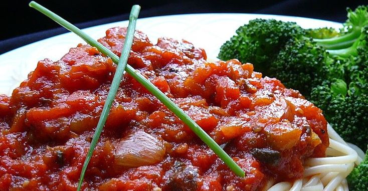 pasta and broccoli on a white plate with red sauce in the middle, ready to be eaten