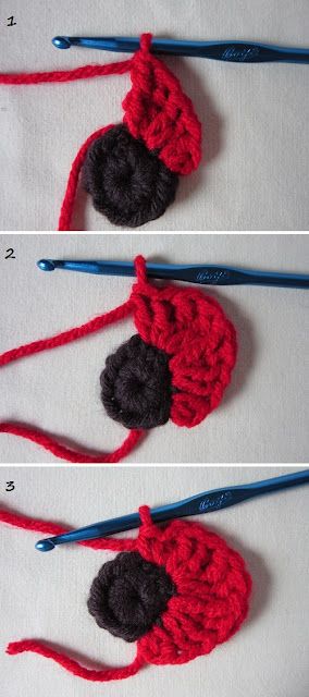 crocheted red and black flower with two blue knitting needles next to each other