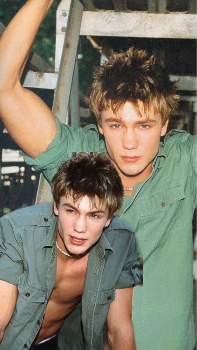 two young men are posing for a photo together, one is leaning on the ladder