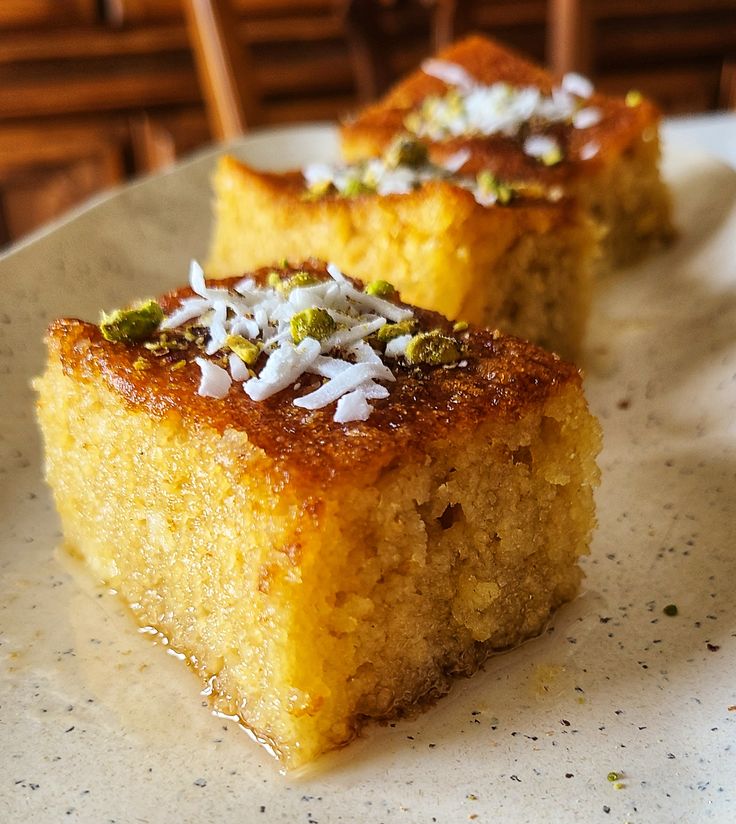 two pieces of cake sitting on top of a white plate covered in coconut flakes