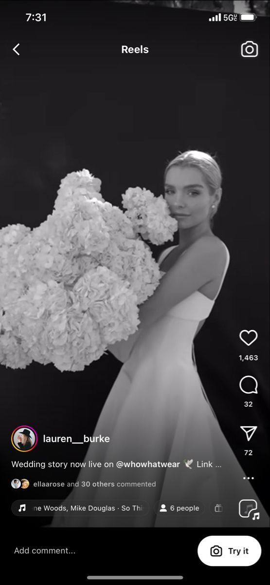 a woman in a white dress is holding a bunch of flowers and looking at the camera