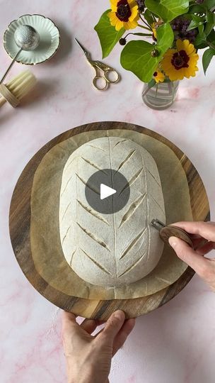 a person is making a bowl out of bread and leaves on a wooden platter