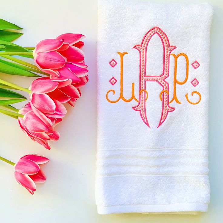 the monogrammed towel is next to pink tulips on a white surface