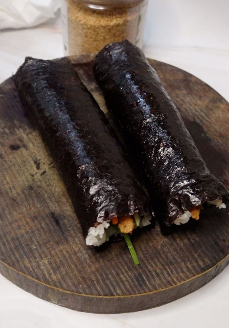 two pieces of sushi on a wooden plate