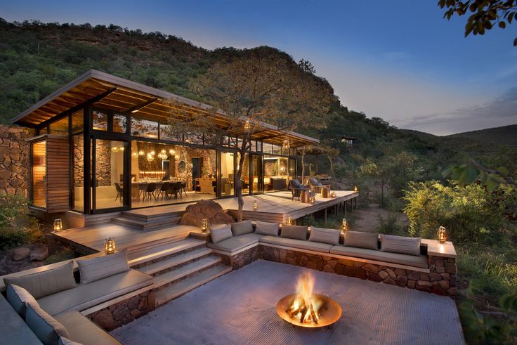 a fire pit in the middle of a patio with steps leading up to it and an outdoor dining area