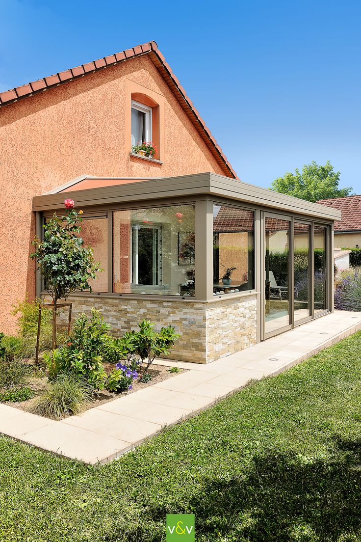 a small house with a patio and covered in glass doors on the side of it