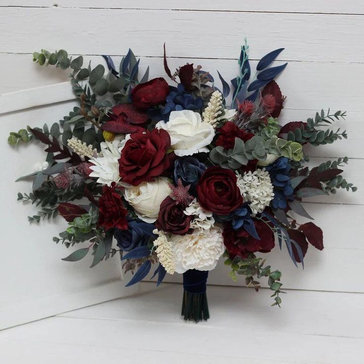 two bridal bouquets with red, white and blue flowers sit on a bench