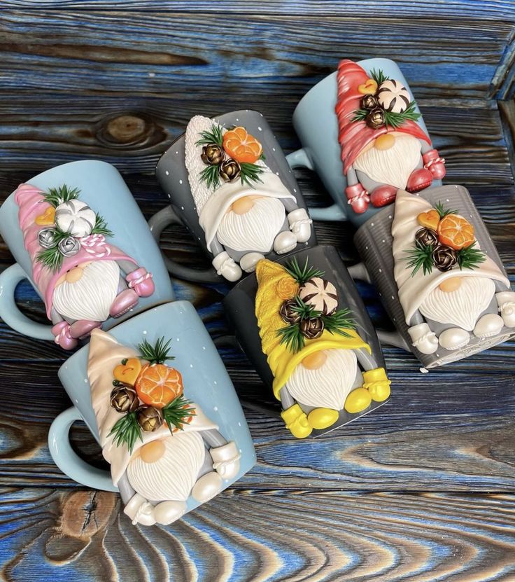 four coffee mugs decorated with santa claus and pine cones on them, sitting on a wooden table