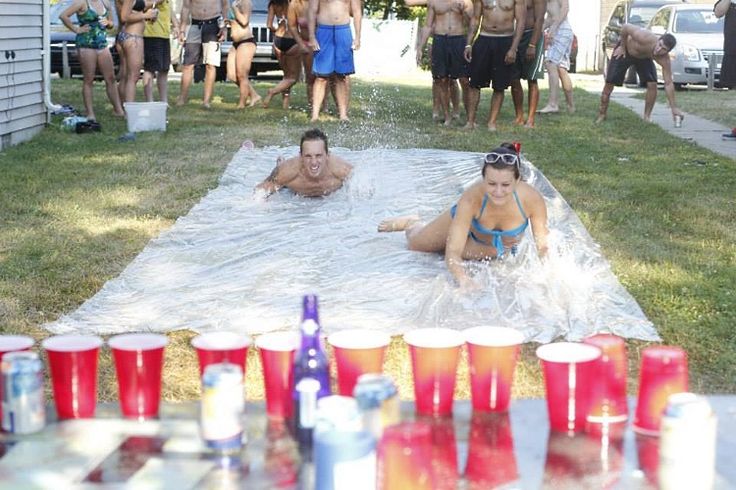 two people are in the water on a blanket with beer glasses and coolers next to them