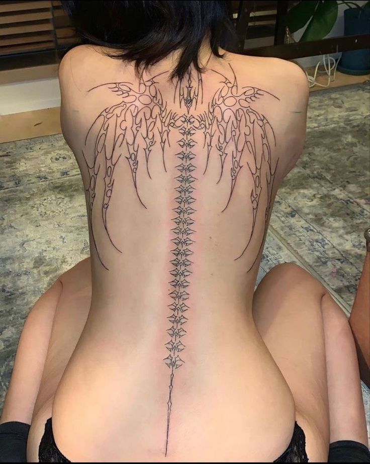 the back of a woman's body with tattoos on it