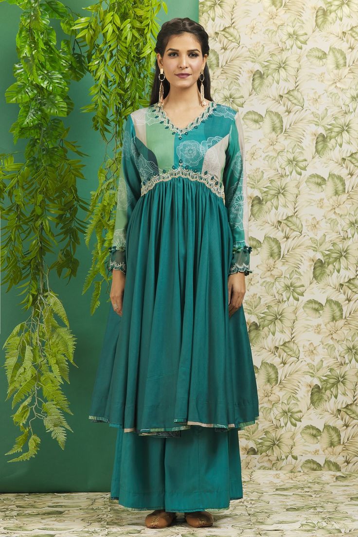 Dark rama green anarkali with floral print on the bodice and mirror work, thread and cutdana embroidery on the neckline and under the bust. Comes with palazzo and border printed dupatta.
Components: 3
Pattern: Print and Embroidery
Type Of Work: Floral Print, Thread, Mirror and Cutdana
Neckline: V neck
Sleeve Type: Long
Fabric: Muslin Silk
Color: Green
Other Details: 
Mirror work dupatta with floral print border
Cuffs with sheer panels and tassel detailing
Scallop trim on the neckline and cuffs
O Designer Green Chanderi Salwar Kameez, Green Chanderi Anarkali Set With Printed Motifs, Green Salwar Kameez With Printed Motifs, Green Anarkali Maxi Dress, Bollywood Style Green Dress For Eid, Green Maxi Length Kurta For Eid, Green Bollywood Dress For Eid, Pista Green Chanderi Anarkali Set With Printed Motifs, Anarkali Salwar Kameez In Pista Green With Printed Motifs