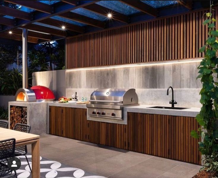 an outdoor kitchen with grill, sink and table