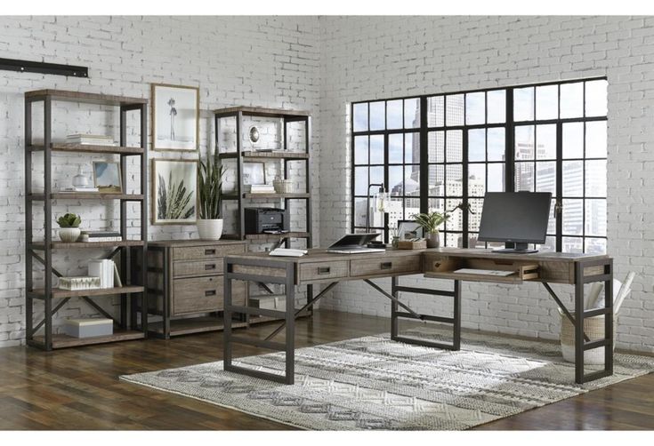 a computer desk sitting on top of a hard wood floor next to a book shelf