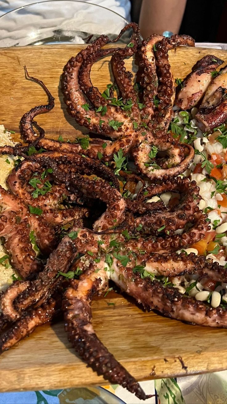 an octopus pizza with various toppings on a wooden cutting board at a restaurant, ready to be eaten