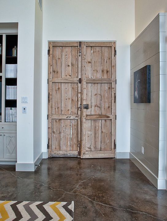 two wooden doors are open in a room with white walls and concrete flooring on the ground