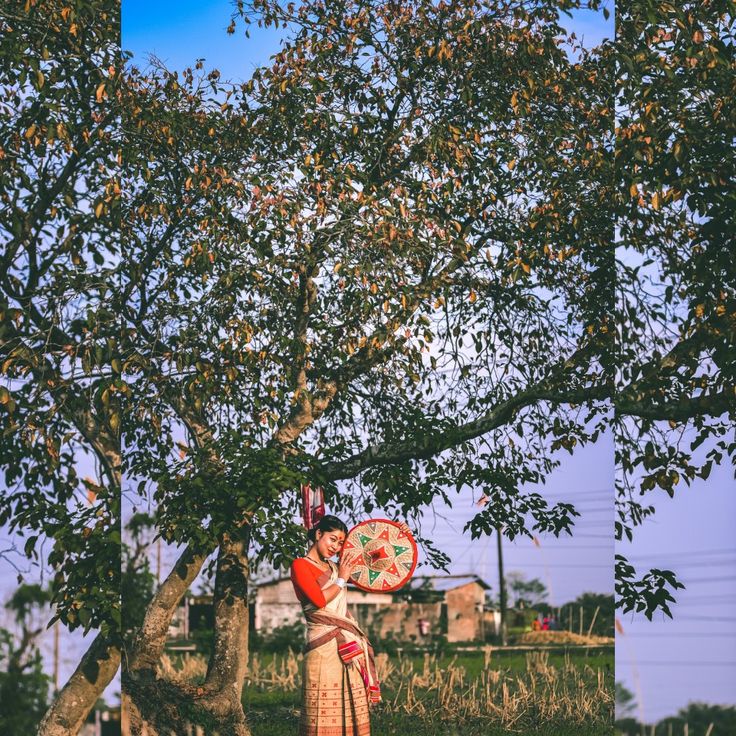 a woman standing under a tree holding a frisbee in her hand and wearing a traditional garb