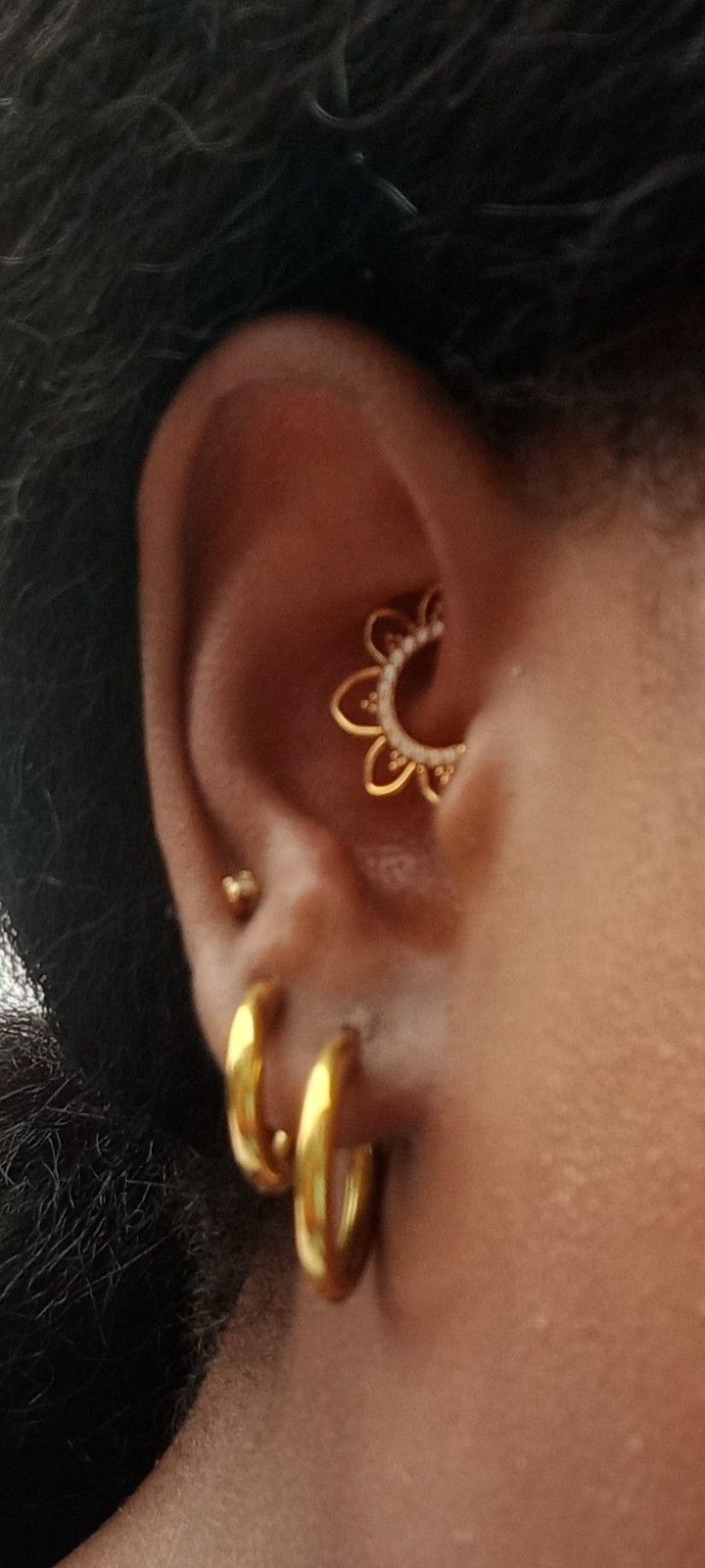 a close up of a person's ear with two gold hoops on it