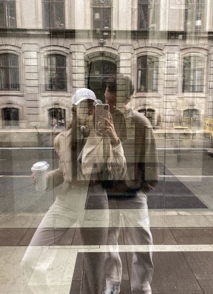 two men walking down the street in front of a building with large windows on each side