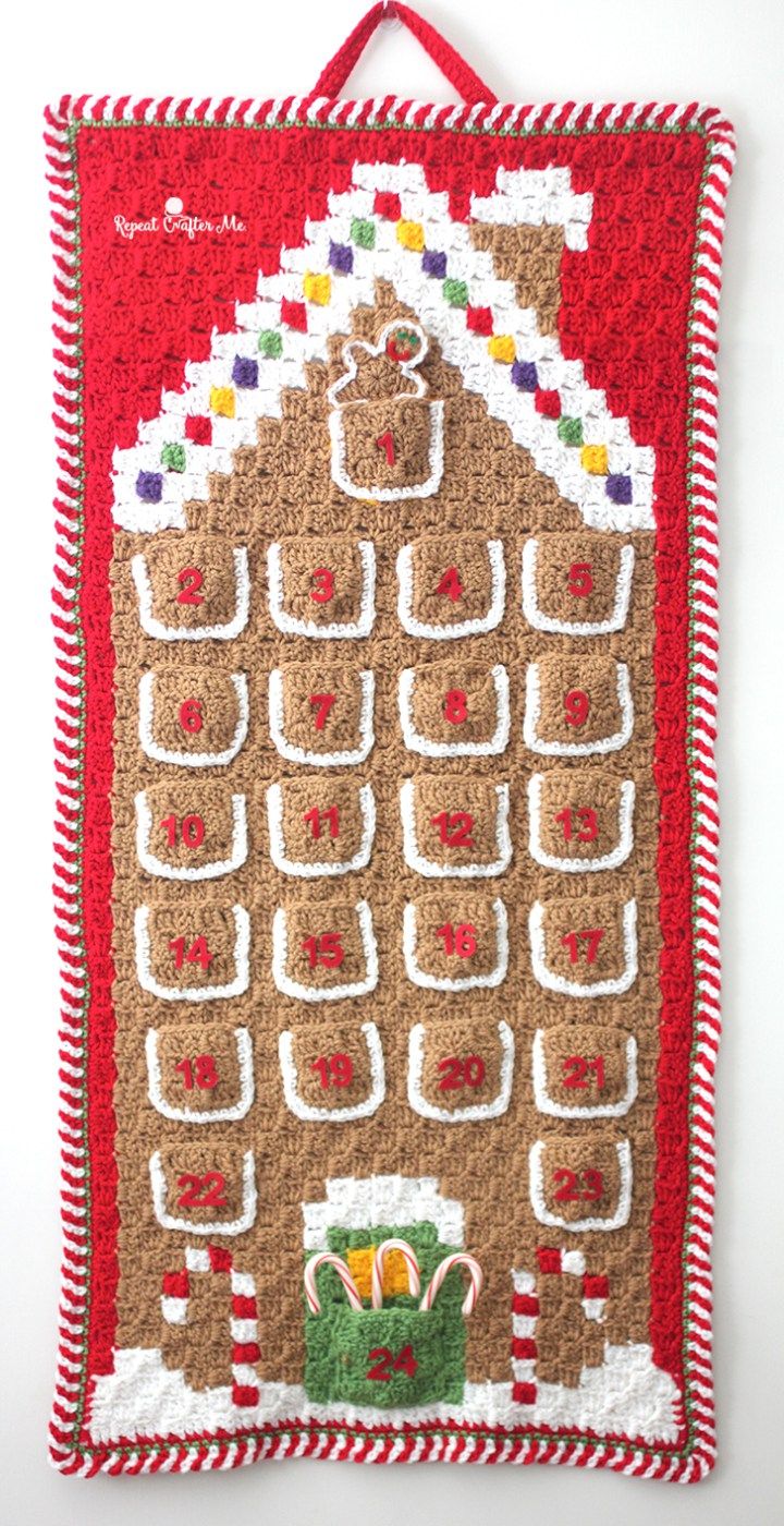 a gingerbread house is hanging on the wall in front of a white background with red and green trim