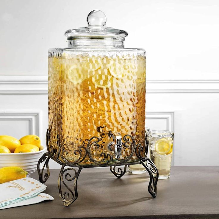 a glass jar filled with liquid sitting on top of a table next to lemons