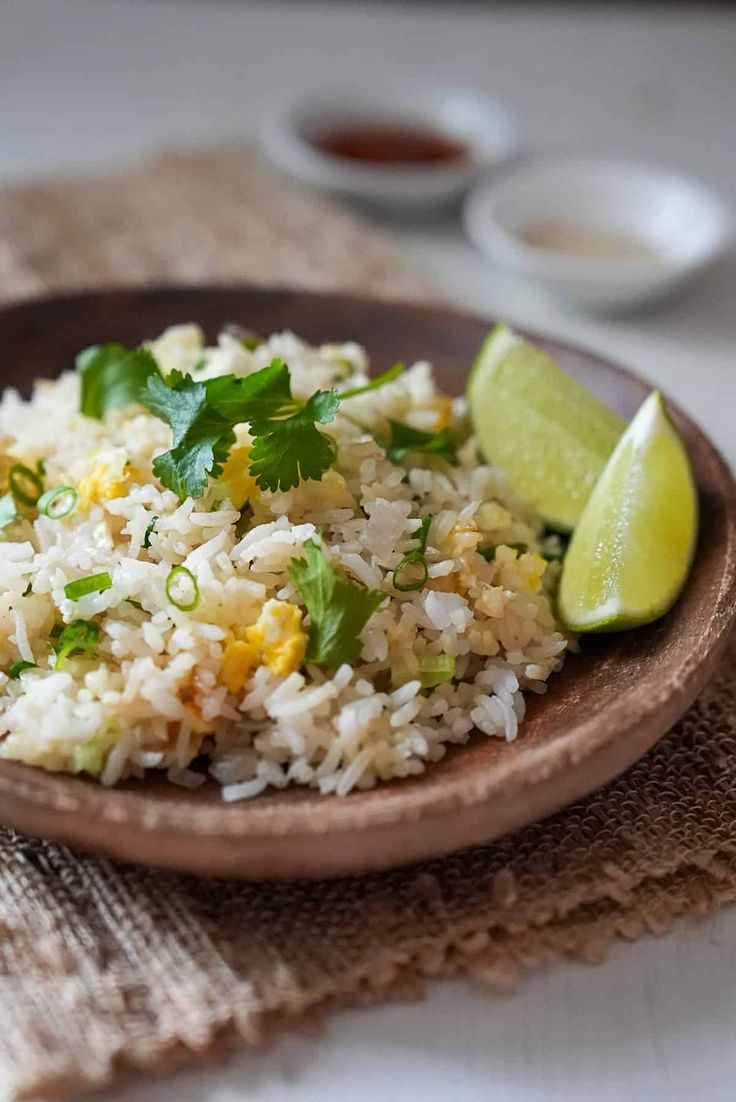 a plate with rice, cilantro and limes on it next to a napkin