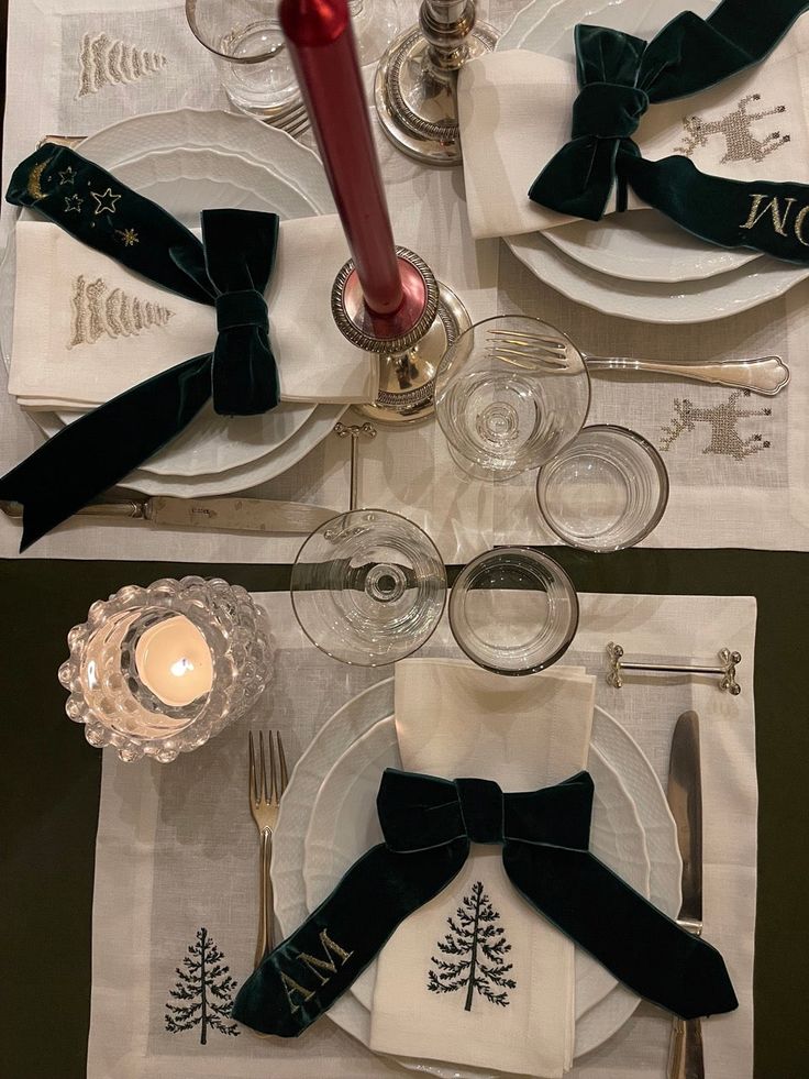 the table is set for christmas dinner with silverware, napkins and place settings