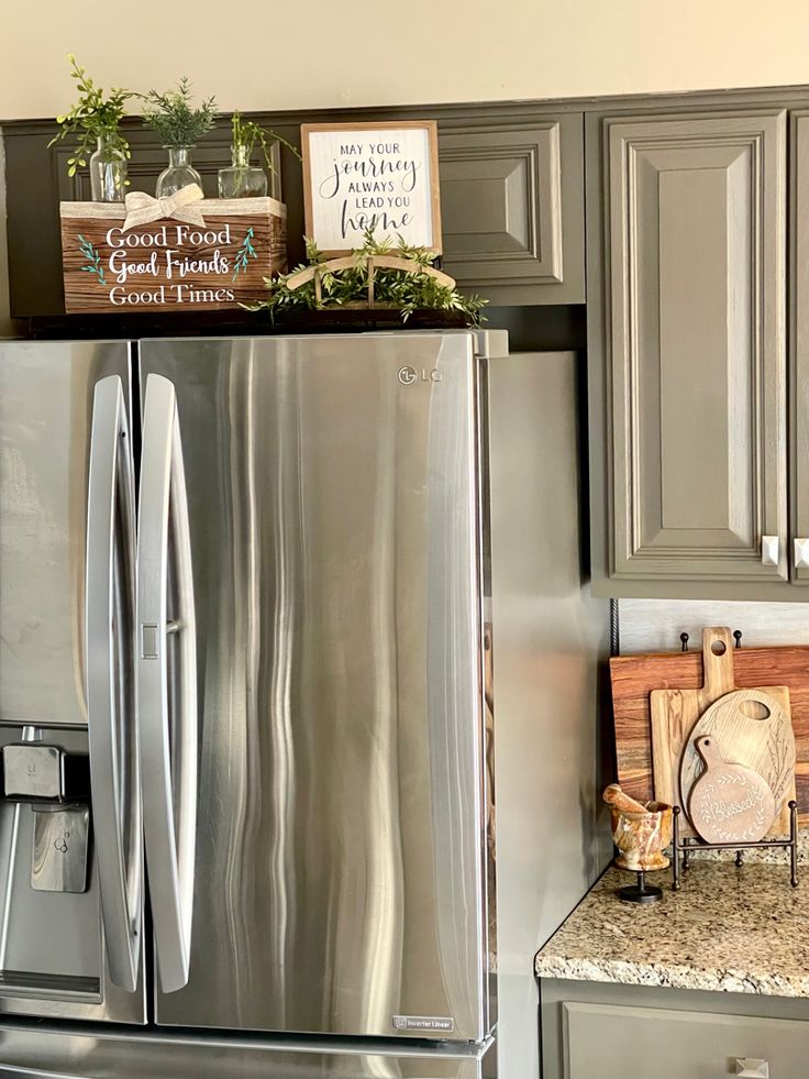 a stainless steel refrigerator in a kitchen with granite counter tops and gray cabinets, along with wooden cutting boards