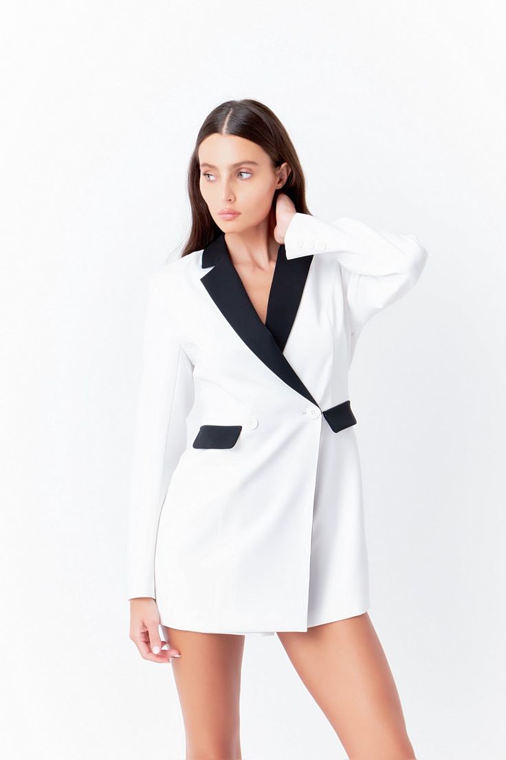 Elevate your style game with our Contrasted Blazer Romper. This versatile piece combines the best of both worlds - the comfort of a romper and the sophistication of a blazer construction. Crafted to flatter your body with its slim fit and long sleeves, this romper is perfect for any occasion. Whether you're headed to a brunch or a night out, this romper will effortlessly take you from day to night. Featuring a unique blend of style and comfort, it is a must-have in your wardrobe. Shop now and make a statement with our Contrasted Blazer Romper. Romper Slim fit Long sleeves Blazer construction Wrapped front with button Hidden side zipper closure Contrast at collar lapel and flap pocket Mini length Lining Hand wash cold Do not bleach Do not tumble dry Iron low Shell: 100% Polyester Contrast: Tailored White Blazer For Night Out, White Tailored Blazer For Night Out, Tailored White Blazer For A Night Out, Spring Workwear Tuxedo Blazer Dress, Semi-formal Tuxedo Blazer Dress For Spring, White Tailored Blazer Dress With Lapel Collar, Chic White Business Pantsuit, Chic White Blazer Dress With Suit Collar, White Semi-formal Blazer Dress With Lapel Collar