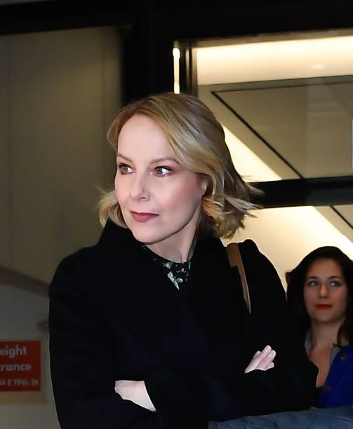 a woman with her arms crossed standing in front of a door and two women behind her