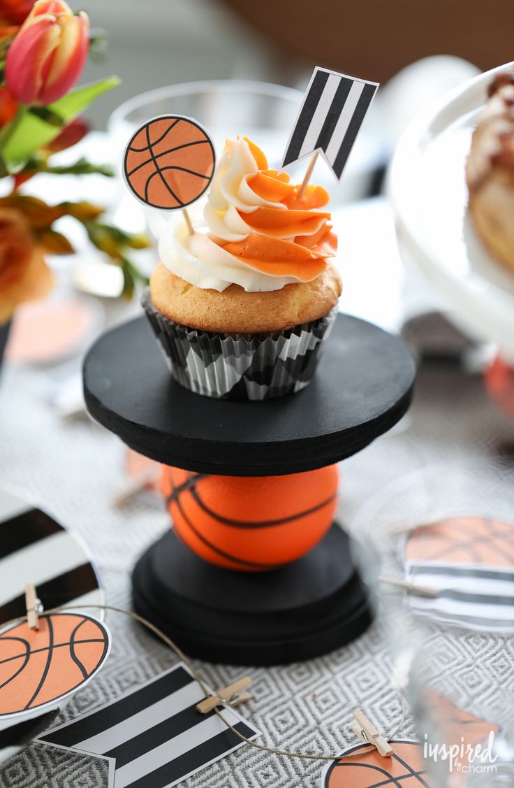 a cupcake on top of a basketball themed cake stand