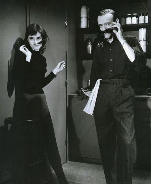 a man and woman standing next to each other in front of a kitchen counter top