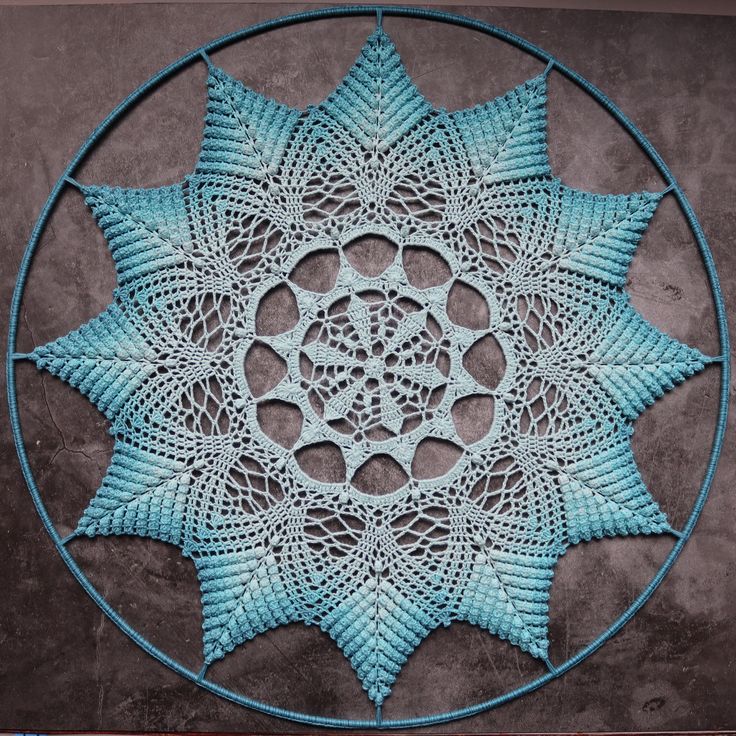 a circular doily with leaves in the center on a concrete surface, ready to be crocheted