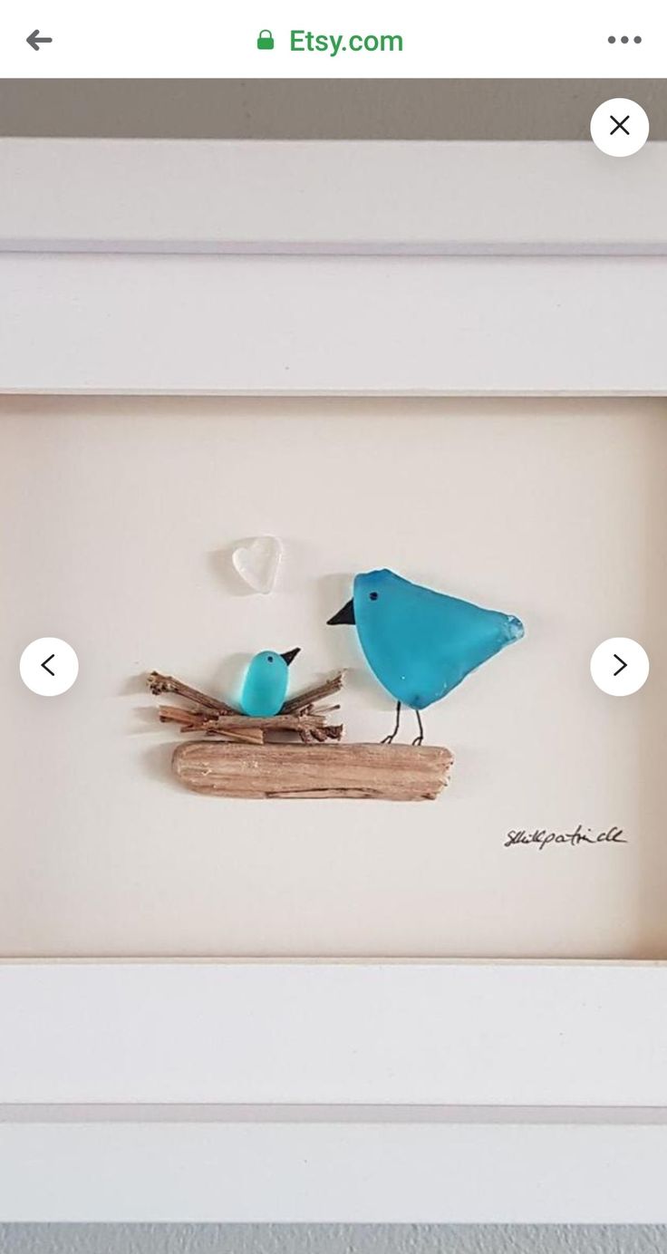 two blue birds sitting on top of a piece of driftwood in a white frame