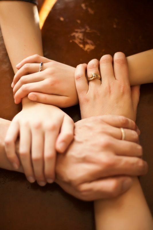 three people holding hands with their fingers on top of each other's arm,