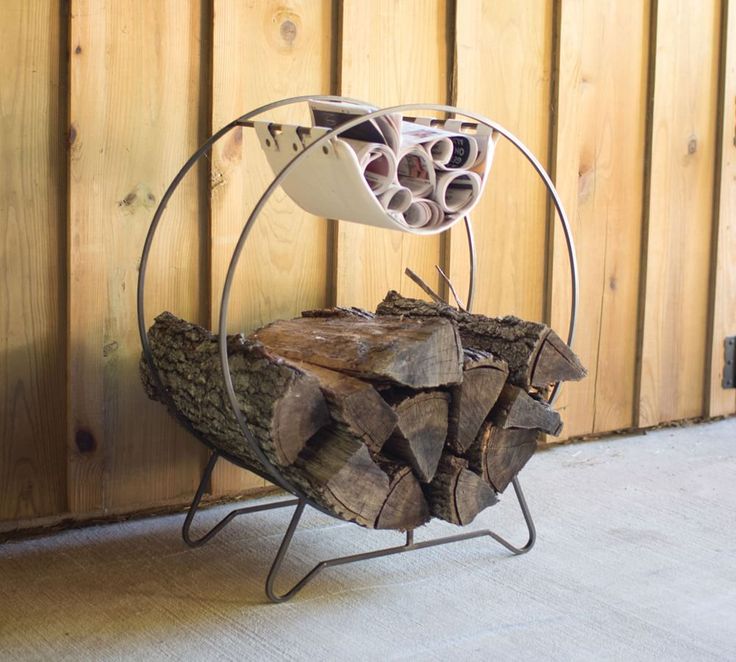 a stack of logs sitting on top of a metal stand next to a wooden wall