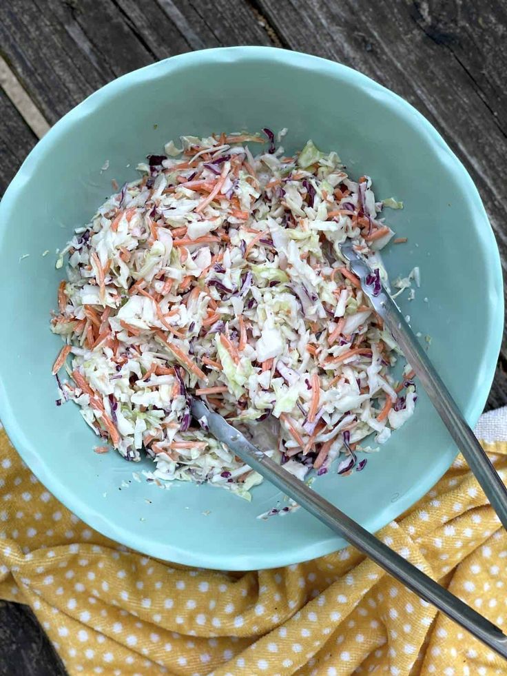 a blue bowl filled with coleslaw on top of a yellow and white towel